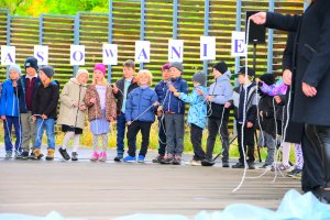 Uczniowie w kolorowych ubraniach pokazują jak wiązać żeglarskie węzły
