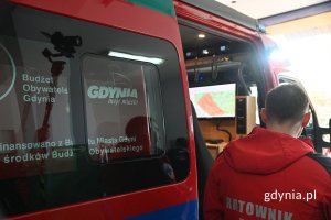 Ratownik medyczny stojący przy otwartych drzwiach czerwonego furgonu