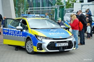 Grupa ludzi przy radiowozie policyjnym podczas festynu „Jestem kibicem”