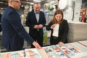 Grupa osób oglądająca maszyny używane do produkcji puzzli i gier