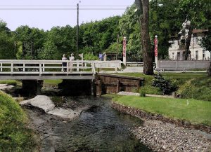 Rzeczka, nad nią most, obok budynek hotelu.