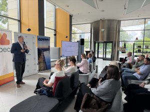 W foyer Muzeum Miasta Gdyni administratorzy i zarządcy budynk&oacute;w słuchają prezentacji, wygłaszanej przez urzędnika. W tle roll-upy PGE Energia Ciepła, OPEC oraz Gdyni.
