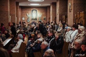 Mieszkańcy siedzący w kościelnych ławach 