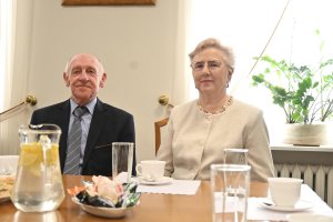 Mężczyzna w garniturze i kobieta w białym kostiumie przy stole