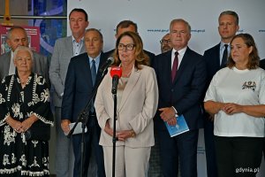Marszałek Senatu Małgorzata Kidawa-Błońska przemawiająca podczaskonferencji prasowej przed wyjazdowym posiedzeniem komisji senackich w Teatrze Muzycznym. Za nią stojący w dwóch rzędach senatorowie