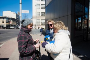 Kobieta w białej kurtce daje innej żonkila
