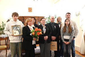 Grupa ludzi, wysoki chłopak trzyma starą fotografię w ręku