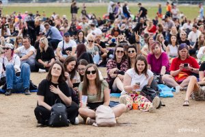 Uczestnicy Open'era  siedzą na trawie na terenie festiwalu // fot. Karol Stańczak