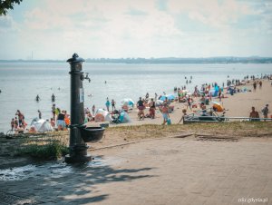 zdrój uliczny, w tle morze i plażujący ludzie