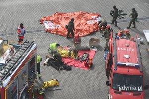 Strażacy i żołnierze rozkładający sprzęt ratowniczy przy wozach strażackich