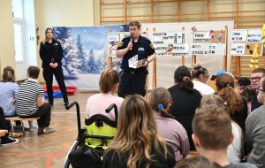 Strażnik miejski pokazuje dzieciom folder