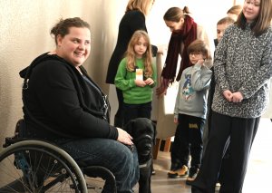 Kobieta na w&oacute;zku inwalidzkim z psem asystującym oraz dzieci