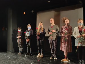 Dzieci ze Szkoły Podstawowej nr 47 i aktorzy na scenie, trzymają róże.