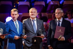 Na zdjęciu trzech uśmiechniętych mężczyzn ze statuetkami