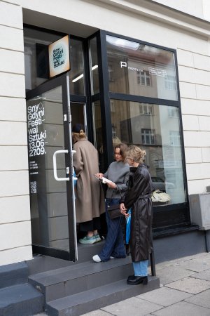Kobiety przy drzwiach i witrynie z napisem: Sny o Gdyni, festiwal sztuki