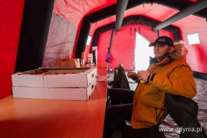 Mężczyzna w ż&oacute;łtej kurtce z paczkiem w dłoni