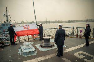 Marynarze wciągają banderę na okręcie