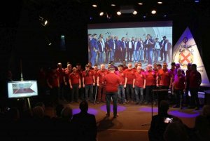 Męski chór stojący śpiewający w sali przed widownią