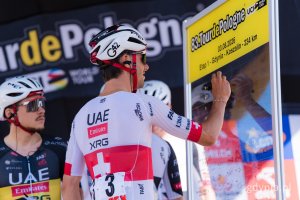 Jeden z zawodnik&oacute;w UAE Team Emirates XRG podpisuje się na tablicy wyścigu 