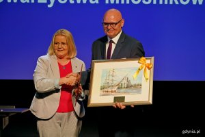 Agnieszka Baranowska &ndash; członkini zarządu wojew&oacute;dztwa pomorskiego przekazuje obraz Wojciechowi Kodłubańskiemu &ndash; prezesowi Towarzystwa Miłośnik&oacute;w Gdyni podczas uroczystości z okazji 50-lecia towarzystwa