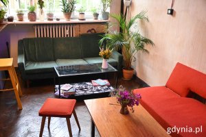 Wnętrze kawiarni „Kosmos” i meble: kanapy, stół oraz kwiaty