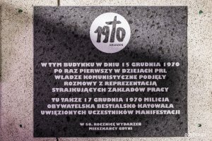 Czarna tablica pamiątkowa na budynku Urzędu Miasta Gdyni odsłonięta w 50. rocznicę wydarzeń Grudnia '70. Widnieje na niej białe logo Grudnia 1970 i biały napis: W tym budynku w dniu 15 grudnia 1970 po raz pierwszy w dziejach PRL władze komunistyczne podjęły rozmowy z reprezentacją strajkujących zakładów pracy. Tu także 17 grudnia 1970 Milicja Obywatelska bestialsko katowała uwięzionych uczestników manifestacji. W 50. rocznicę wydarzeń - mieszkańcy Gdyni // fot. Karol Stańczak