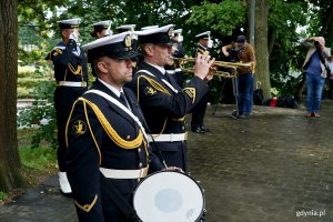 Trębacz i werblista, a w tle salutujący żołnierze Marynarki Wojennej RP podczas uroczystości  z okazji 87. rocznicy wybuchu II wojny światowej na Cmentarzu Wojennym w Redłowie