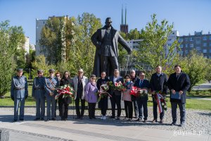Ludzie z kwiatami po pomnikiem