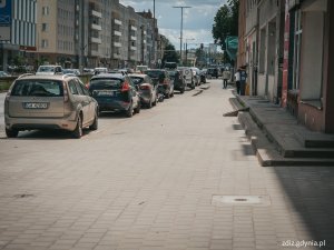 Chodnik na ul. Śląskiej po remoncie, widoczne budynki, samochody, oznakowanie