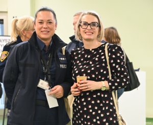 Kobieta w czarnej sukience i kobieta w mundurze policyjnym.