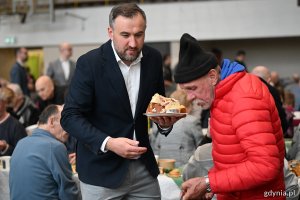 Dyrektor zarządzający ds. społecznych Tomasz Augustyniak podaje gościom ciast