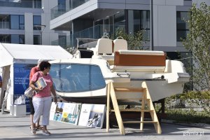 Kobieta i mężczyzna idący nabrzeżem w Marinie Yacht Parku w Gdyni przyglądają się kremowo-niebieskiemu jachtowi // fot. Magdalena Czernek