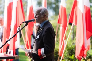 Starszy mężczyzna w garniturze na tle flag