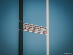 tablica z napisem "muzeum miasta Gdyni", na tle nieba