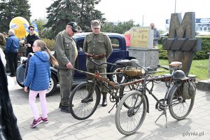 Mężczyźni w mundurach z czasów II wojny światowej stoją przy wojskowych rowerach z epoki.