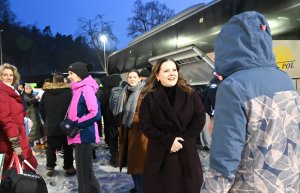 Ludzie przed autokarem, na pierwszym planie kobieta w płaszczu