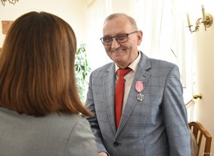 Starszy pan w szarym garniturze z szerokim uśmiechem