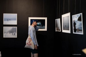 Mężczyzna na tle zdjęć podczas wernisażu wystawy &bdquo;Gdynia Gł&oacute;wna&rdquo; w Galerii Gdyńskiego Centrum Filmowego