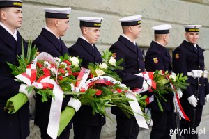 Żołnierze w mundurach Marynarki Wojennej z wiązankami kwiatów