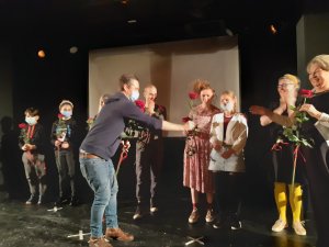 Dzieci ze Szkoły Podstawowej nr 47 i aktorzy na scenie, wręczane im są róże i gratulacje.