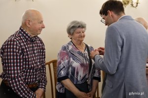 Para z mężczyzną w garniturze, kt&oacute;ry trzyma medal