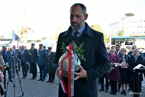Doradca społeczny prezydenta RP Tomasz Szturo składający znicz pod tablicą pamiątkową, kt&oacute;ra znajduje się na fasadzie Dworca PKP Gdynia Gł&oacute;wna, podczas uroczystości z okazji 87. rocznicy pierwszych wysiedleń Gdynian 