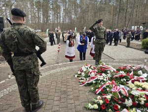 Osoby w strojach kaszubskich składają kwiaty pod Pomnikiem Ofiar Piaśnicy