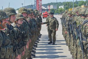 Żołnierze Morskiej Jednostki Rakietowej podczas powitania w porcie Wojennym w Gdyni. Żołnierze stoją ustawieni w dwóch szeregach. Środkiem idzie komandor Przemysław Karaś – dowódca Morskiej Jednostki Rakietowej  // fot. por. mar. Cezary Skwierawski