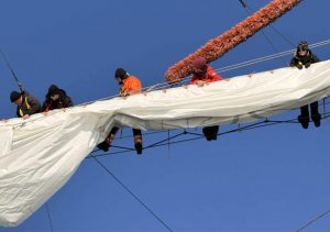 Uczniowie odbywający praktyki morskie na &bdquo;Darze Młodzieży&rdquo; stawiający żagiel stulecia Gdyni na maszcie żaglowca 