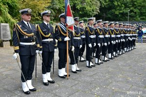 Żołnierze Marynarki Wojennej, honorowa asysta wojskowa, w mundurach podczas uroczystości 80. rocznicy zbrodni katyńskiej. Jeden z nich trzyma w ręku sztandar // fot. Magdalena Czernek