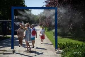 Ludzie korzystający z kurtyny wodnej na skwerze