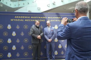 Mężczyźni fotografują się na tle nazwy wydziału