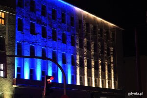 Budynek Urzędu Miasta Gdyni podświetlony wieczorem niebiesko-żółtymi światłami.