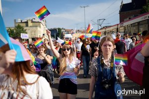 Grupa osób z tęczowymi flagami i transparentami